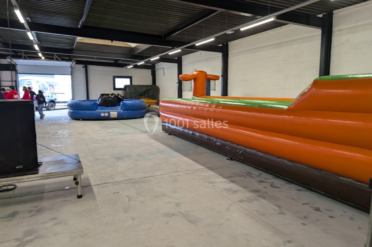 Structure intérieure avec des jeux gonflables colorés installés dans un espace industriel lumineux.