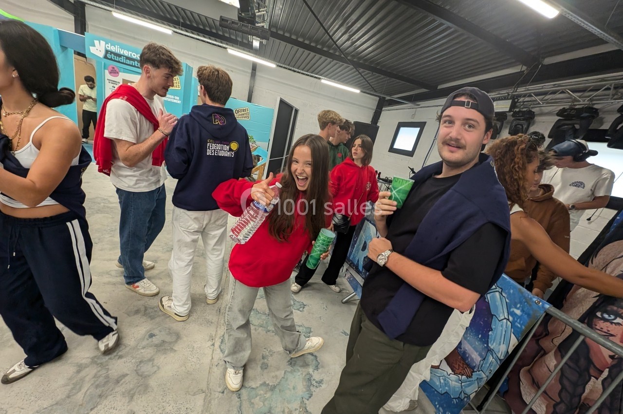 Des jeunes discutent et rient dans un espace intérieur moderne, certains tenant des bouteilles d'eau.