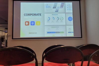 Des enfants colorient des dessins autour d'une table ronde, entourés d'adultes dans un espace intérieur animé.