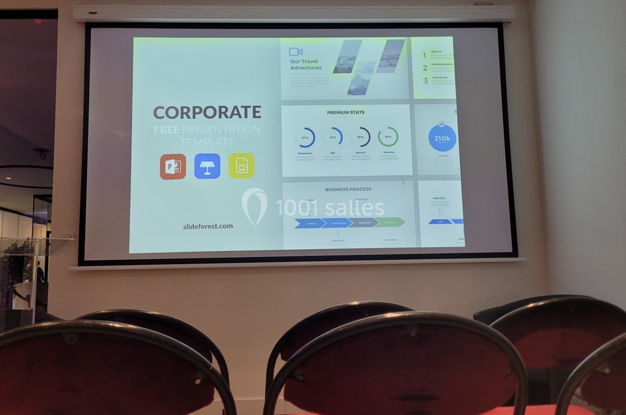 Écran de présentation affichant un modèle de diaporama d'entreprise dans une salle avec des chaises vides au premier plan.