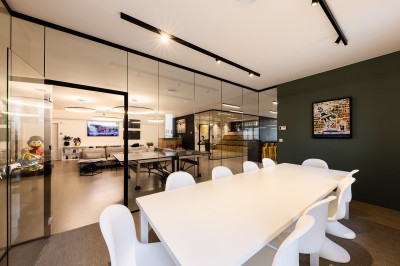 Des enfants colorient des dessins autour d'une table ronde, entourés d'adultes dans un espace intérieur animé.