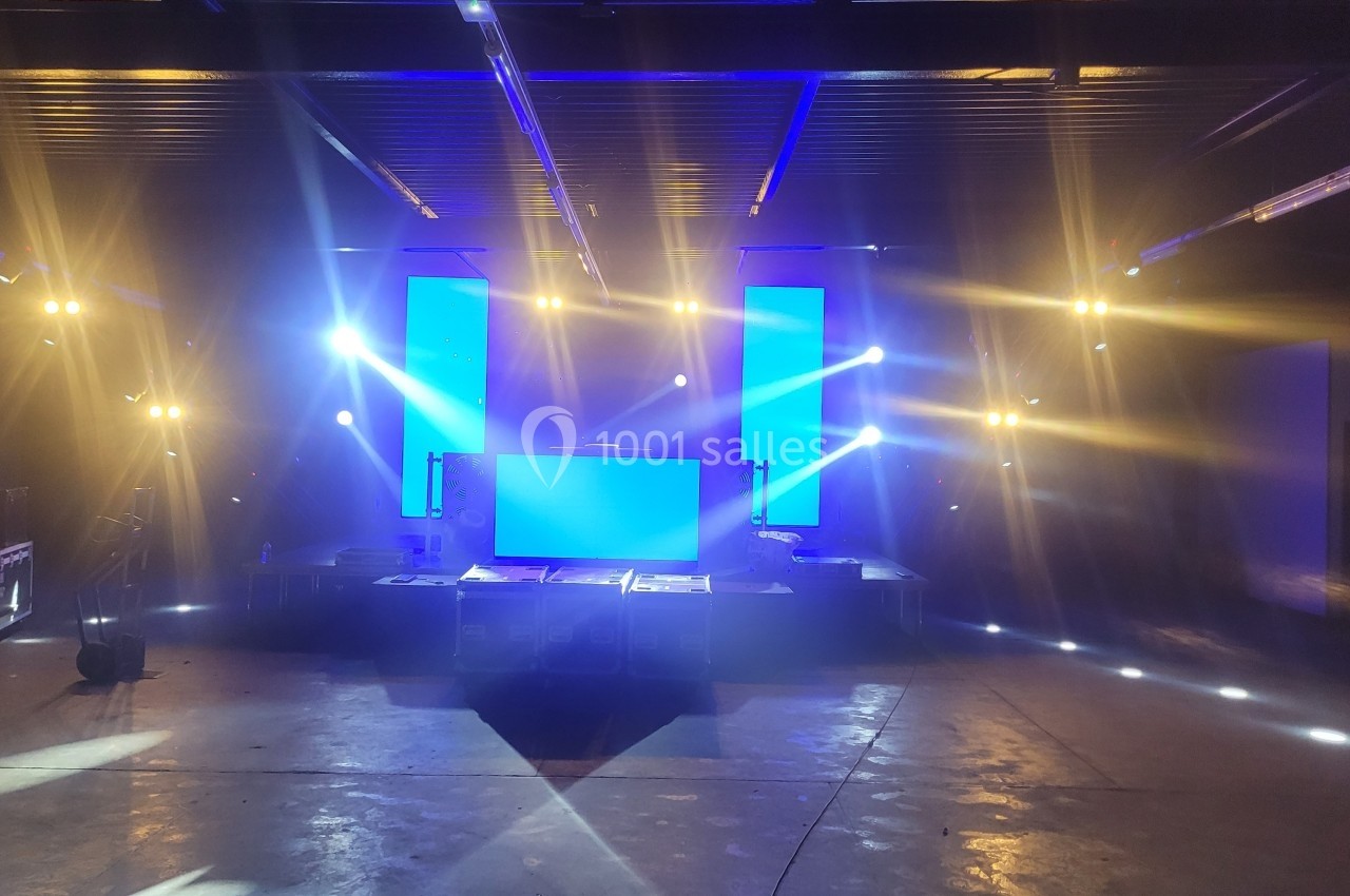 Scène intérieure avec éclairage coloré et écrans lumineux bleus, prête pour un événement ou une performance.