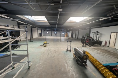 Des enfants colorient des dessins autour d'une table ronde, entourés d'adultes dans un espace intérieur animé.