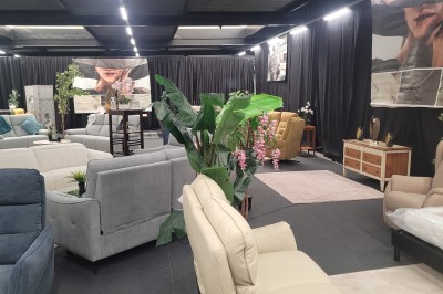 Des enfants colorient des dessins autour d'une table ronde, entourés d'adultes dans un espace intérieur animé.