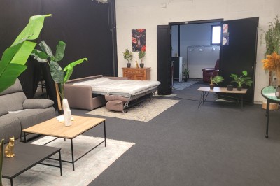 Des enfants colorient des dessins autour d'une table ronde, entourés d'adultes dans un espace intérieur animé.