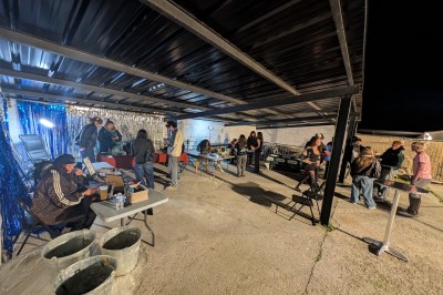 Des enfants colorient des dessins autour d'une table ronde, entourés d'adultes dans un espace intérieur animé.