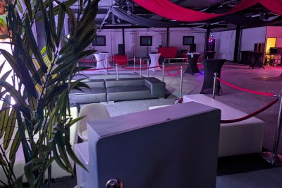 Deux mascottes en ours, blanc et rose, posent debout dans un espace intérieur animé avec des visiteurs.