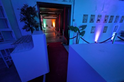 Deux mascottes en ours, blanc et rose, posent debout dans un espace intérieur animé avec des visiteurs.