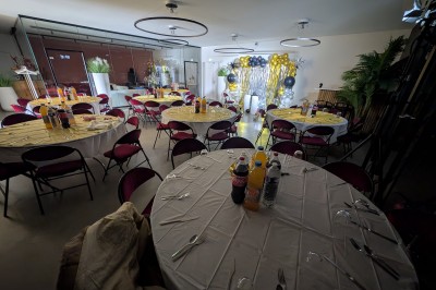 Deux mascottes en ours, blanc et rose, posent debout dans un espace intérieur animé avec des visiteurs.