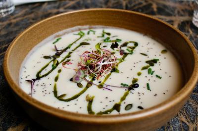 Salle de réunion moderne avec tables disposées en U, chaises en bois, éclairage suspendu et écran mural.