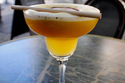 Salle de réunion moderne avec tables disposées en U, chaises en bois, éclairage suspendu et écran mural.