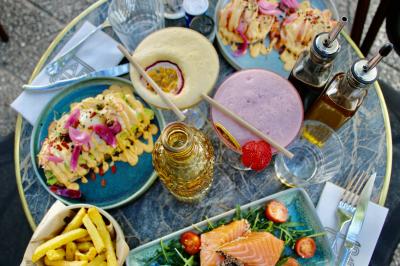 Salle de réunion moderne avec tables disposées en U, chaises en bois, éclairage suspendu et écran mural.