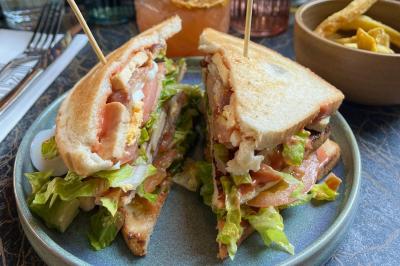 Salle de réunion moderne avec tables disposées en U, chaises en bois, éclairage suspendu et écran mural.