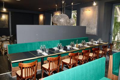 Salle de réunion moderne avec tables disposées en U, chaises en bois, éclairage suspendu et écran mural.