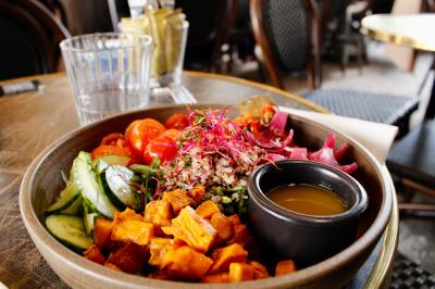 Salle de réunion moderne avec tables disposées en U, chaises en bois, éclairage suspendu et écran mural.