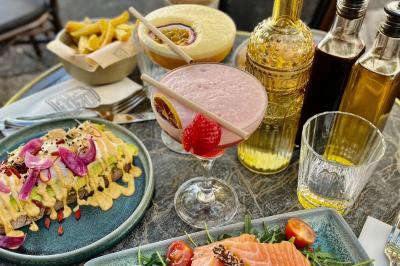 Salle de réunion moderne avec tables disposées en U, chaises en bois, éclairage suspendu et écran mural.