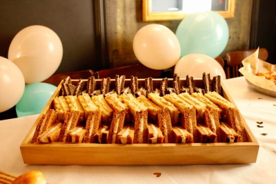 Salle de réunion moderne avec tables disposées en U, chaises en bois, éclairage suspendu et écran mural.