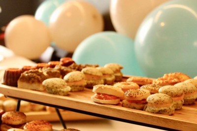 Salle de réunion moderne avec tables disposées en U, chaises en bois, éclairage suspendu et écran mural.