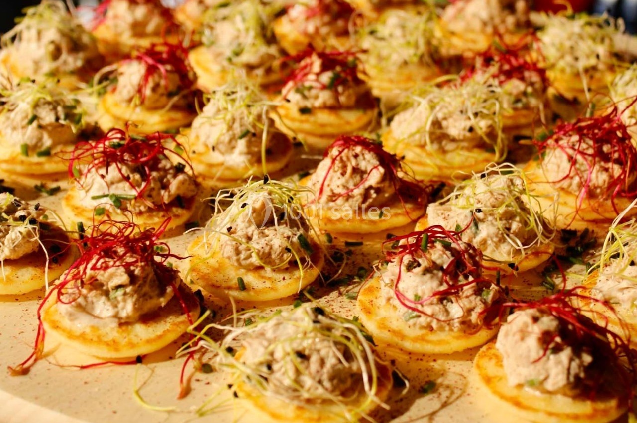 Assortiment de bouchées sur des rondelles de polenta garnies de crème et décorées de pousses et de légumes râpés.