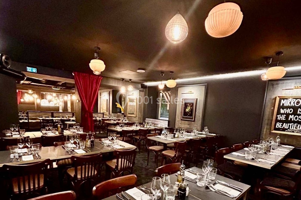 Salle de restaurant élégante avec tables dressées, éclairage tamisé et décorations murales modernes.