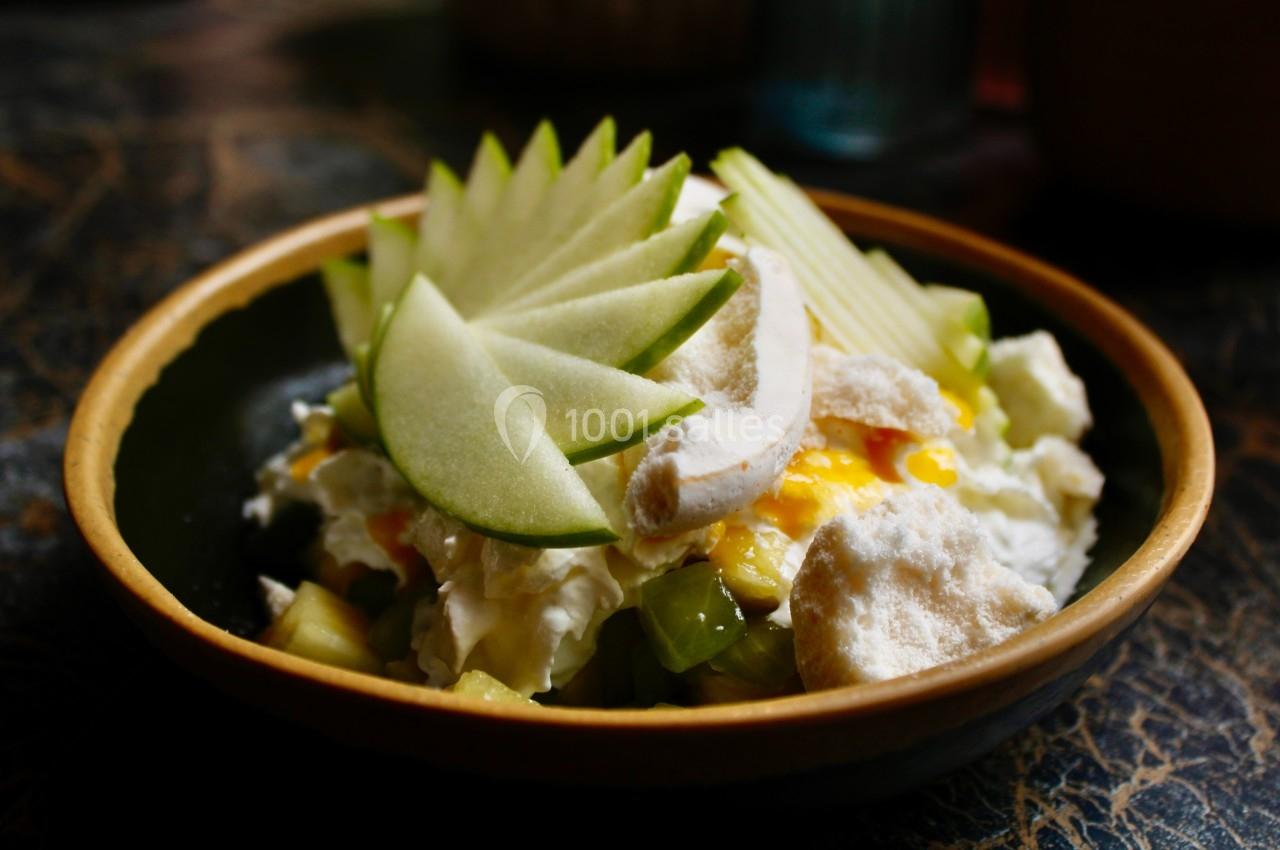 Bol contenant une salade de fruits garnie de tranches de pomme verte, de meringue et de crème.