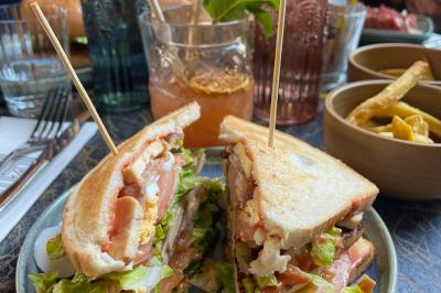 Deux verres de jus colorés sur une table en terrasse, l'un décoré de menthe et d'une tranche d'orange séchée.