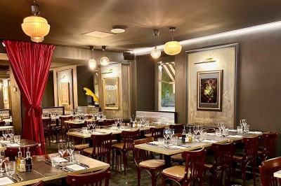 Deux verres de jus colorés sur une table en terrasse, l'un décoré de menthe et d'une tranche d'orange séchée.