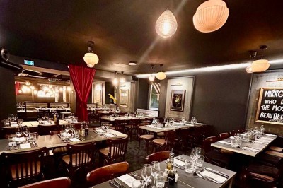 Deux verres de jus colorés sur une table en terrasse, l'un décoré de menthe et d'une tranche d'orange séchée.