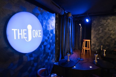 Enseigne lumineuse rouge avec l'inscription ’Private Joke’ dans un environnement sombre.