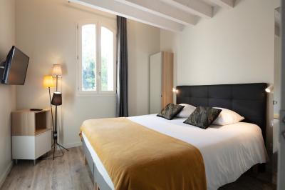 Grande table dressée en extérieur avec des chaises en bois, sous une pergola illuminée de lumières violettes, devant un…