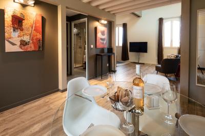 Grande table dressée en extérieur avec des chaises en bois, sous une pergola illuminée de lumières violettes, devant un…