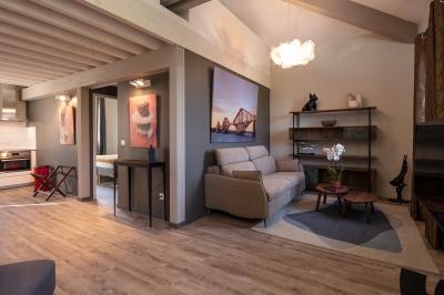 Grande table dressée en extérieur avec des chaises en bois, sous une pergola illuminée de lumières violettes, devant un…