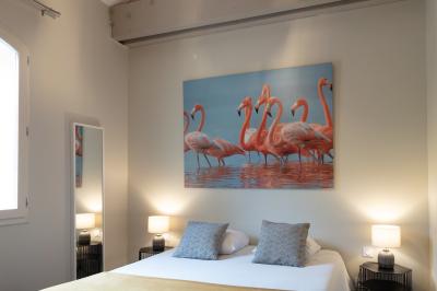 Grande table dressée en extérieur avec des chaises en bois, sous une pergola illuminée de lumières violettes, devant un…