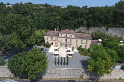 Grande table dressée en extérieur avec des chaises en bois, sous une pergola illuminée de lumières violettes, devant un…