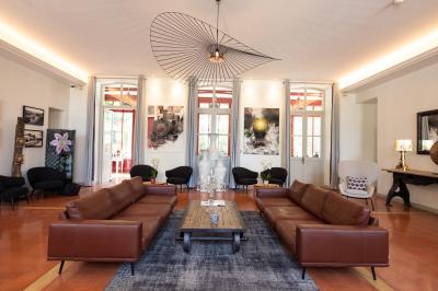 Grande table dressée en extérieur avec des chaises en bois, sous une pergola illuminée de lumières violettes, devant un…
