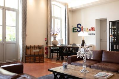 Grande table dressée en extérieur avec des chaises en bois, sous une pergola illuminée de lumières violettes, devant un…