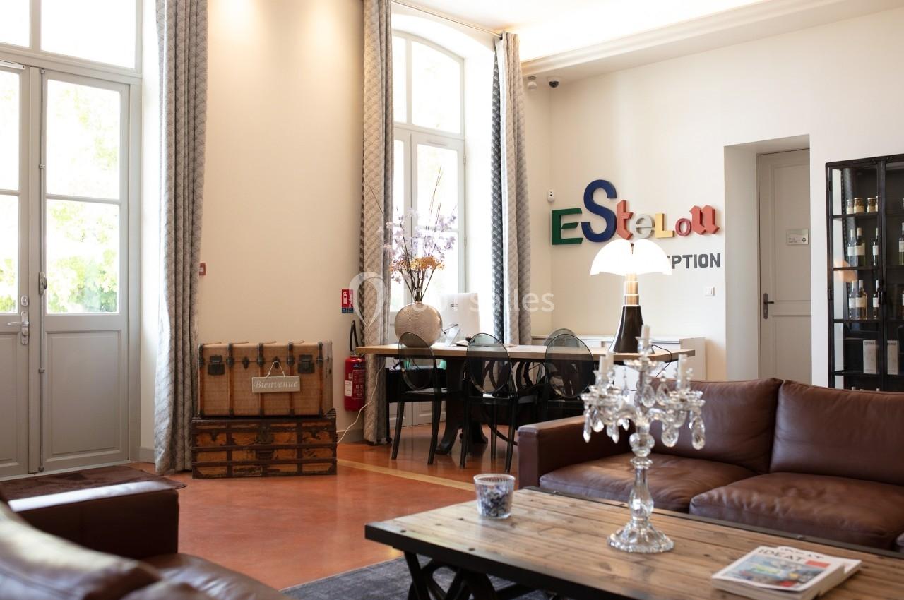 Salon lumineux avec canapés en cuir, table basse, décoration vintage et logo coloré sur un mur clair.