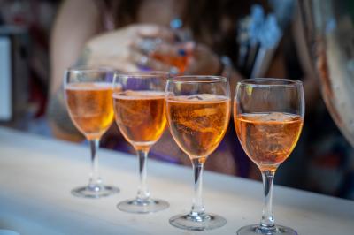 Grande table dressée en extérieur avec des chaises en bois, sous une pergola illuminée de lumières violettes, devant un…