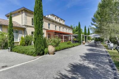 Grande table dressée en extérieur avec des chaises en bois, sous une pergola illuminée de lumières violettes, devant un…