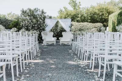 Grande table dressée en extérieur avec des chaises en bois, sous une pergola illuminée de lumières violettes, devant un…