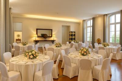 Grande table dressée en extérieur avec des chaises en bois, sous une pergola illuminée de lumières violettes, devant un…