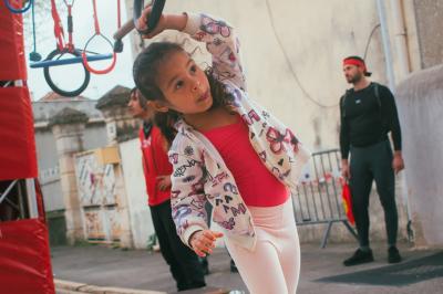 Deux acrobates exécutent une figure d'équilibre sur une caisse, devant un public dans un espace éclairé.