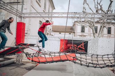 Parcours d'obstacles intérieur avec structures suspendues et ballons rouges, sous un éclairage de salle de loisirs.