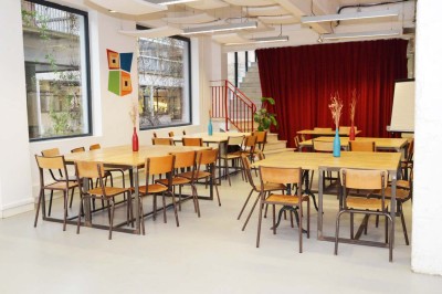 Salle de réunion avec une table rectangulaire, chaises noires, un tableau à feuilles mobiles et des décorations murales…