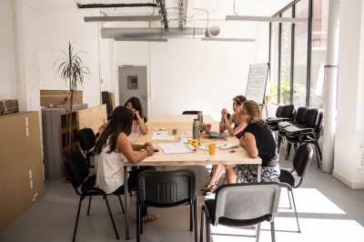 Salle de réunion avec une table rectangulaire, chaises noires, un tableau à feuilles mobiles et des décorations murales…
