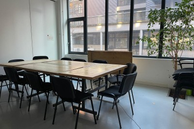 Salle de réunion avec une table rectangulaire, chaises noires, un tableau à feuilles mobiles et des décorations murales…