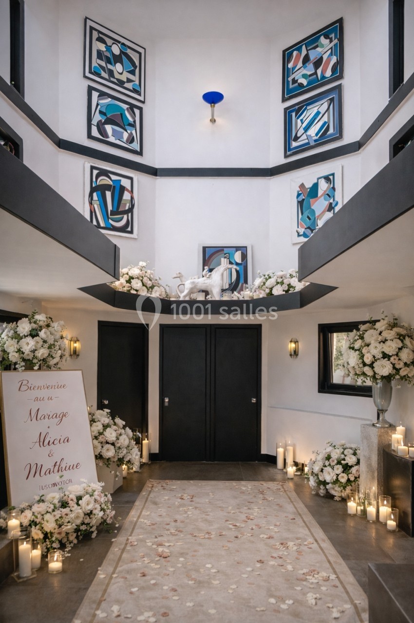 Entrée décorée pour un mariage avec fleurs blanches, bougies, tapis beige et panneau de bienvenue.
