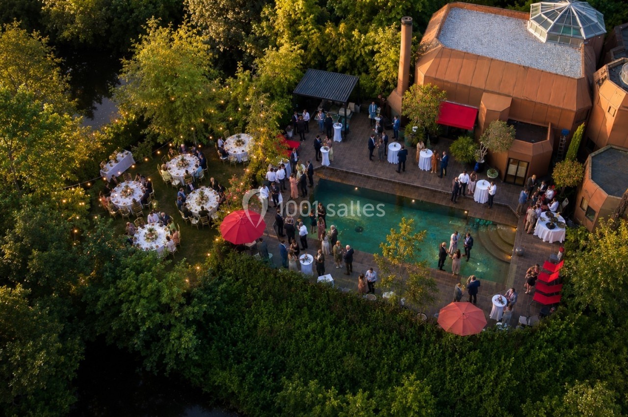 Vue aérienne d'une réception en plein air avec piscine, tables dressées et invités entourés de verdure.