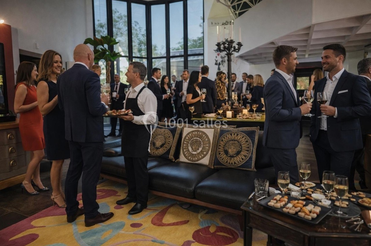 Groupe de personnes en tenue élégante discutant et dégustant des amuse-bouches lors d'un événement dans un salon moderne.