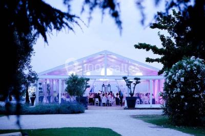 Vue aérienne d'un domaine rural avec bâtiments en pierre, arbres et vue sur une étendue d'eau calme en arrière-plan.